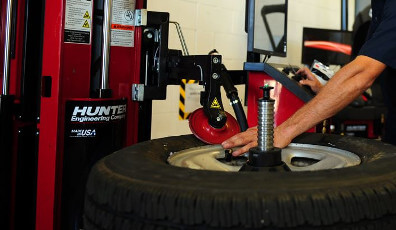 Mechanic performing tire and wheel service with a tire changer